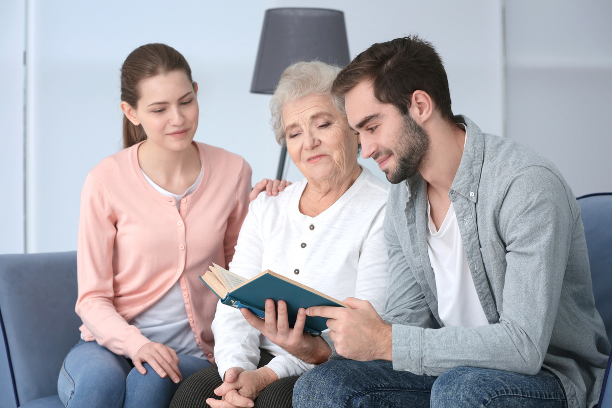 Grandmother with grandchildren reading book on sofa