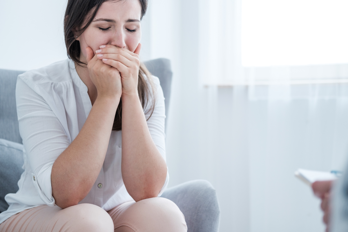 A stressed crying young woman covering her mouth