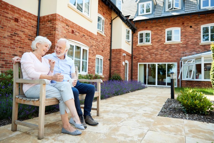 Retired Couple Sitting On Bench With Hot Drink 