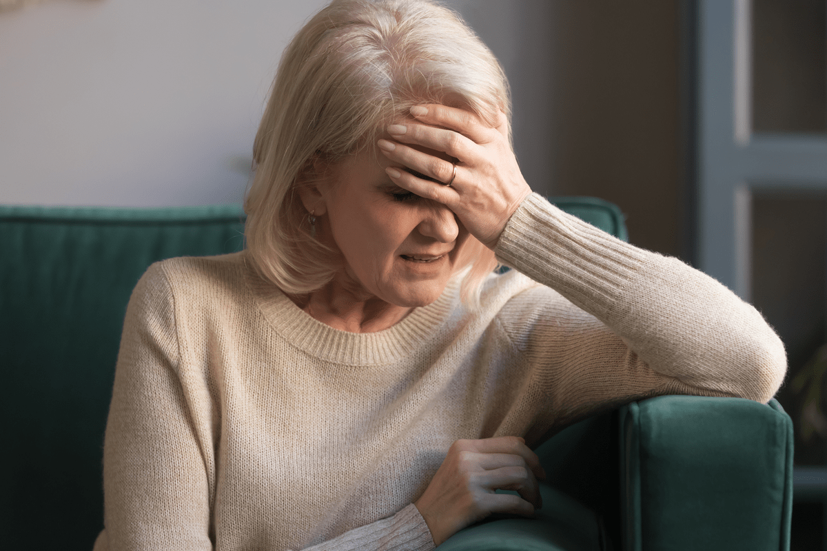 Unhappy mature grey haired woman suffering from headache
