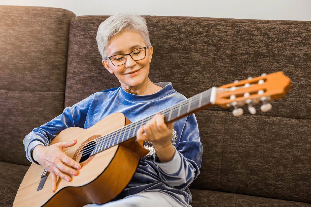 Stylish adult woman playing guitar