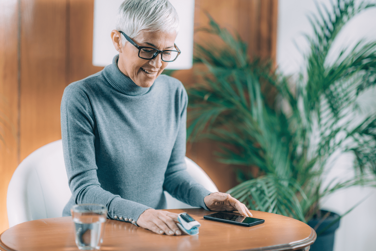 Senior Woman Using Pulse Oximeter and Smart Phone