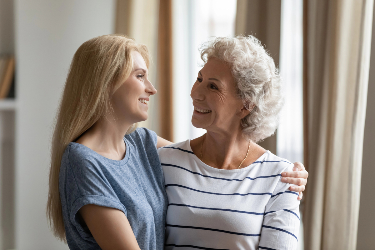 Happy mature mother cuddling warm smiling 