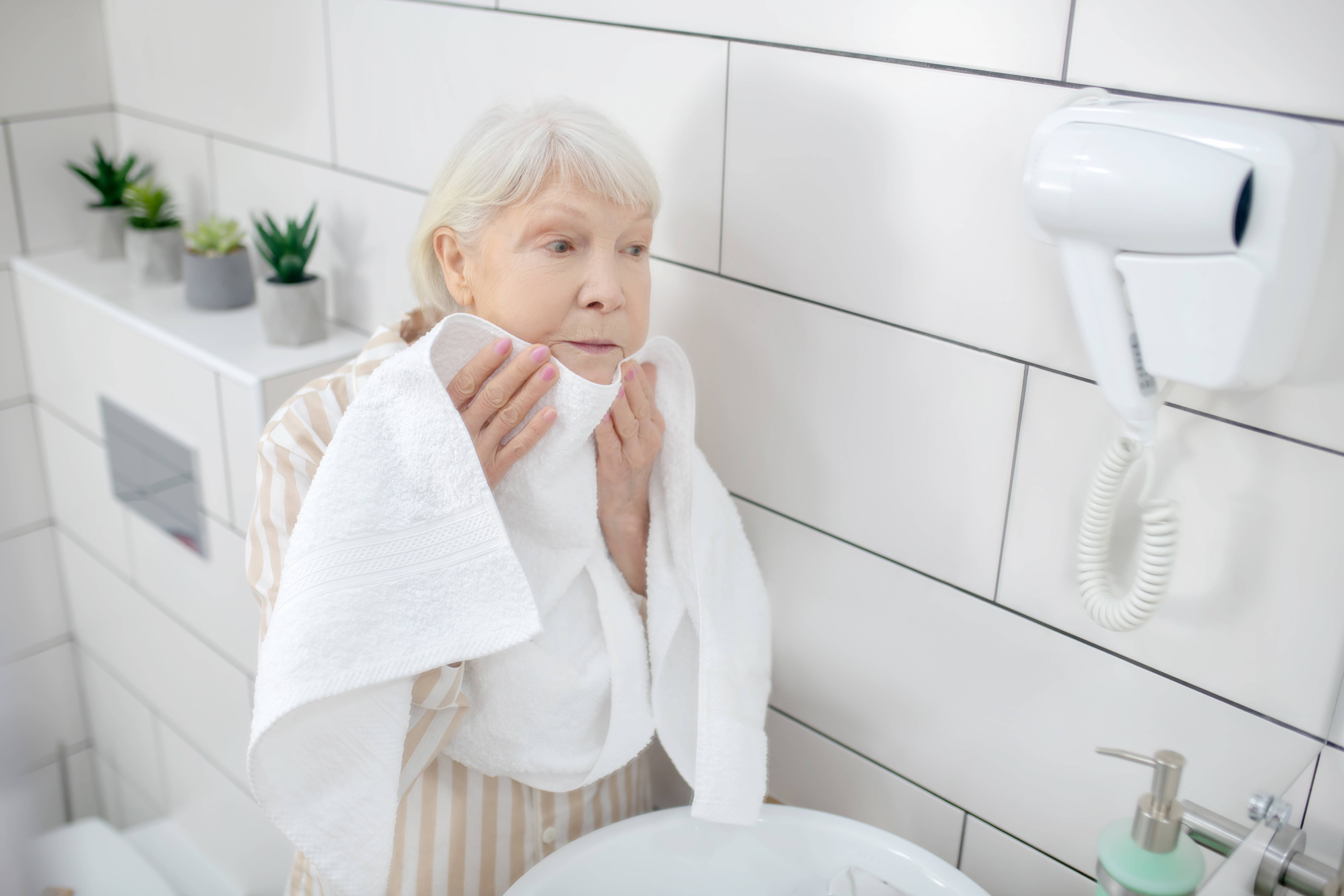 Gray-haired woman drying her face
