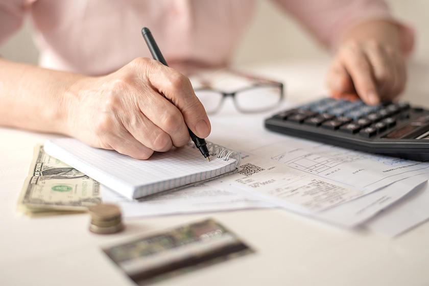Pension calculation concept, old hands counting finances on a home calculator , close- up 